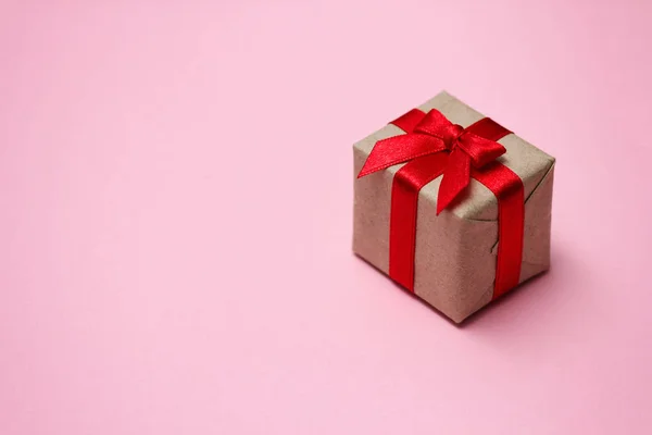 礼品盒用褐色工艺纸包好 系上红色缎带 粉色坚实的背景 销售概念 横向横幅图片格式 你的文字空间 — 图库照片