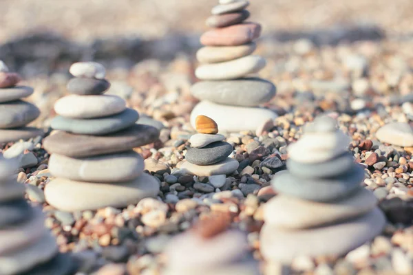 Zen pyramid of spa stones on the blurred sea background. Sand on a beach. Sea shores. Place for text.