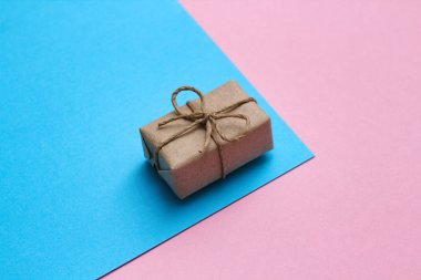 Cinsiyet belirleme günü konsepti. El işi kağıt ve kravat ipliğine sarılı bir hediye kutusu. Pembe ve mavi arka planlar. Kız ya da erkek. Doğum günü partisi. 