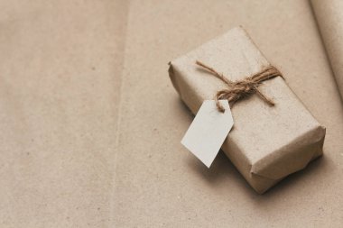 Paket kahverengi el işi kağıdıyla sarılıp kenevir ipliğine bağlanmış. Kağıt etiketli paket. Teslimat servisi. İnternetten alışveriş. Satın alın. Hediye kutusu masanın üstünde. Kenevir iplikleri.