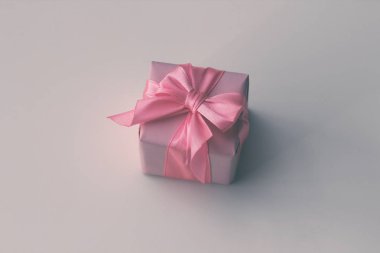 El işi kahverengi kağıda sarılı bir hediye kutusu ve pembe saten kurdele. Beyaz arkaplan. 