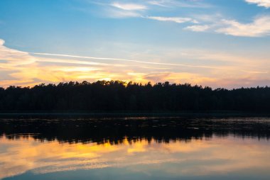 (At sunrise) gün batımında Ormanla göl manzaralı görünümünü. Gölü akşam balık tutma