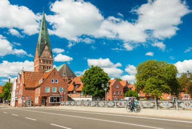 Luneburg - Temmuz 2018, Aşağı Saksonya, Almanya: köprünün yürüyüş insanlar. Katedrali ve tarihi eski evler mavi gökyüzü ve bulutlar arka planda