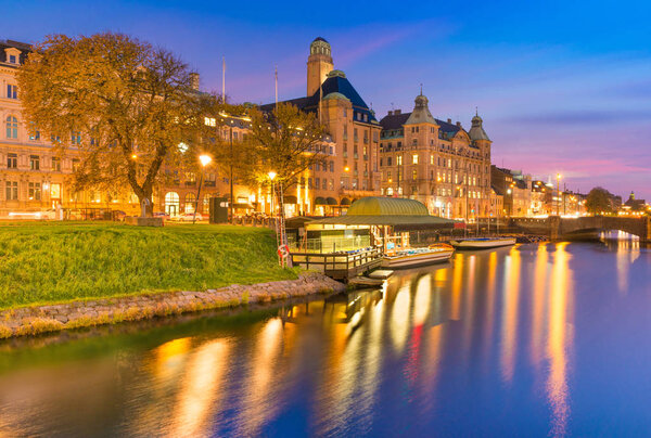 Beautiful sunset in Malmo, Sweden. Picturesque evening cityscape. Old historical buildings, canal with boats at the wharf, colorful reflections in water