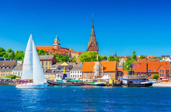 Cityscape Flensburg. Kuzey Almanya küçük bir Avrupa kasabada Panoraması. Bir yelkenli bir liman eski mimari, gemi ve arka planda yerlerinden olan kıyı şeridi boyunca yüzen