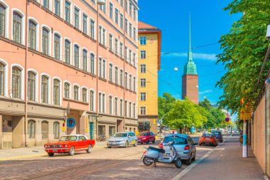Helsinki - Haziran 2019, Finlandiya: Araba trafiğine sahip bir sokak, Mikael Agricola Kilisesi ve renkli konut binaları