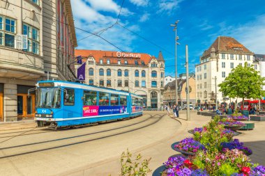 Oslo - Haziran 2019, Norveç: Oslo 'nun merkezinde mavi tramvayı, eski tarihi binaları ve güzel çiçek tarlaları olan bir sokak manzarası