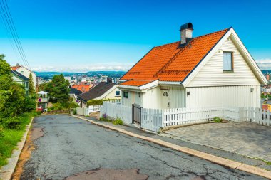 Oslo - Haziran 2019, Norveç: Şehrin etrafındaki tepelerden birinde boş bir caddenin manzarası. Turuncu çatılı ahşap beyaz ev 
