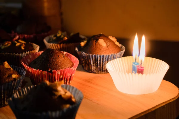 Çikolata muffin yanan muma yanındaki ahşap bir gemide. Sıcak ışık. Tatlı. Ev rahatlık. Homemade Pişirme.