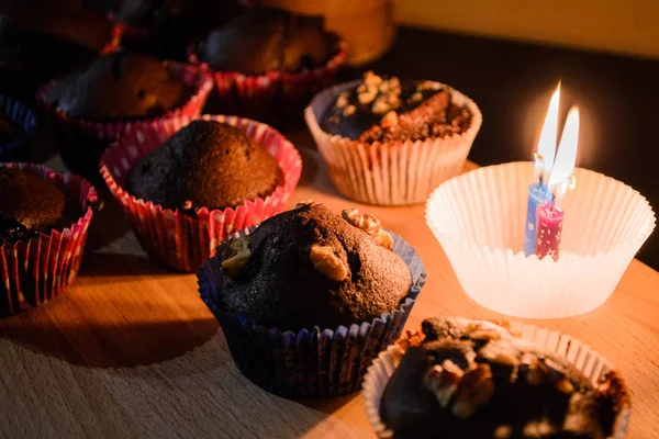 Çikolata muffin yanan muma yanındaki ahşap bir gemide. Sıcak ışık. Tatlı. Ev rahatlık. Homemade Pişirme.