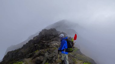 Dağcı zirve doğru seyir sisli dağ ortasında ayakta dinlenme sırt ile