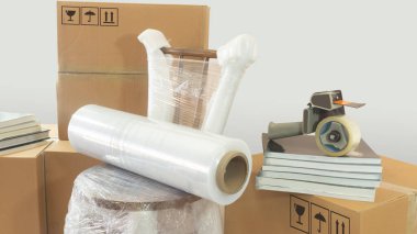 Plastiğe sarılı, kapalı karton kutular, kitaplar ve beyaz arka planda maskeleme bandı olan bir sandalyeye plastik rulo ile taşınan sahne