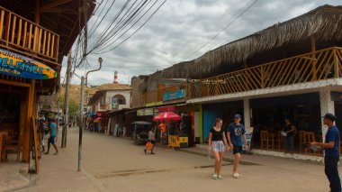 Mancora, Piura / Peru - 8 Nisan 2019: Bulutlu bir günde köyün ana caddesinde yürüyen iki turist