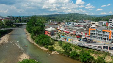 Tena, Napo / Ekvador - 10 Ekim 2020: Ekvador Amazon kentindeki Tena kentindeki Napo nehrinin sahil yolunda yürüyen insanların panoramik manzarası