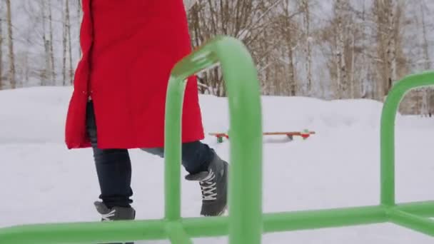 Frau geht allein in Winterlandschaft bei launischem Wetter Wandermädchen trägt rote Jacke mit Kapuze Spaziergang in verschneiter Landschaft — Stockvideo