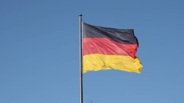 Mavi gökyüzü gününde rüzgarda dalgalanan Alman bayrağının yatay fotoğrafı..