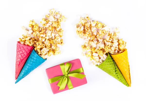 Caramel popcorn in waffle cup. Festive sweets, caramel popcorn, waffles and a gift box. Gift box on white background.