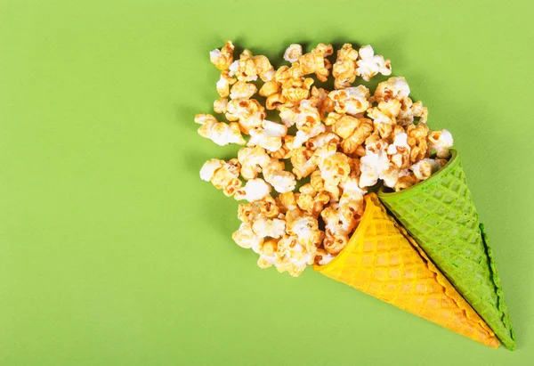 Golden caramel popcorn in wafer cone. Summer sweets. Two waffle cones and scattered popcorn. Sweet air corn. Copy space