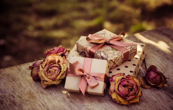 Gift boxes and dry roses. Dried flowers and craft gift box. stack of gifts and dried flowers. Gifts in brown paper