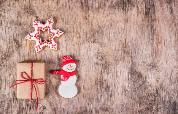 Homemade gingerbread cookie and gift box on wooden background. Handmade holiday sweets. Christmas cookies. Copy space. Top view