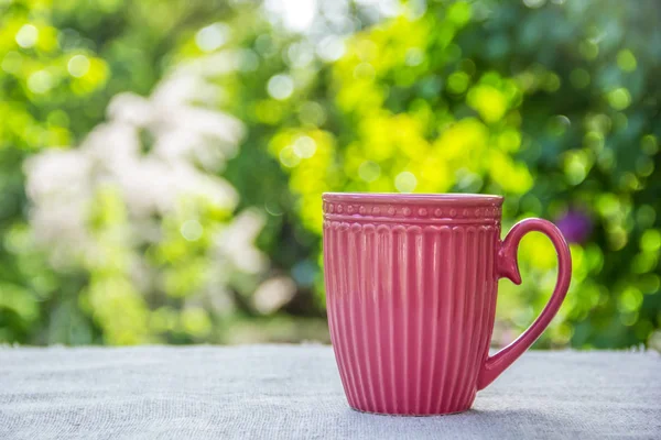Morning coffee in the garden. Pink mug. Cup of tea. Copy space