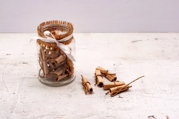 A glass jar with notes of craft paper. Light background.