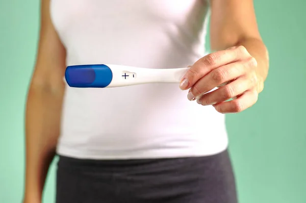 The girl holds in her hand a positive pregnancy test. The beginning of pregnancy. Pregnancy proof. Selective focus.