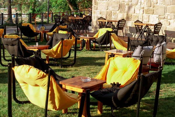 Armchairs bags and tables on the grass in a cafe. The interior of the summer cafe. Summer furniture in a restaurant.