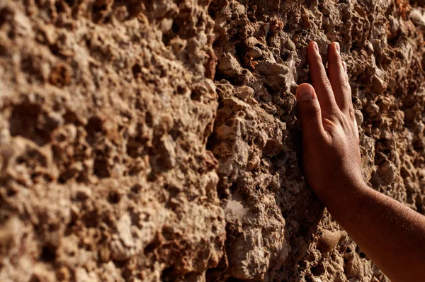 Hand touches an antique limestone wall close-up. Touch of antiquity.