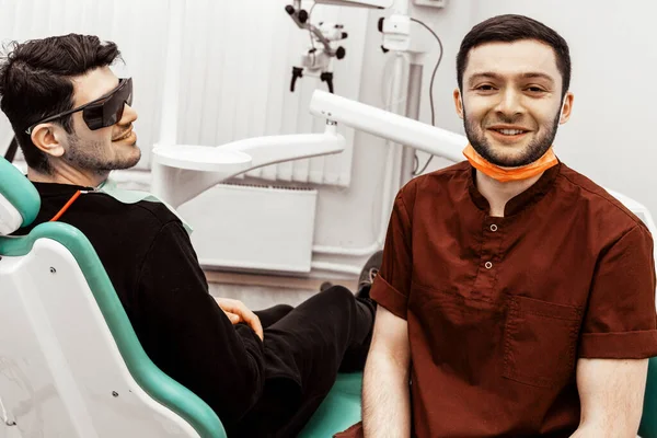 A young dentist discusses a diagnosis and treatment plan with a patient. Discussion and demonstration of treatment results. Health care, aesthetic medicine.
