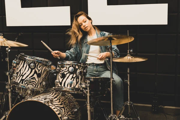 Creativity and music. Young beautiful girl plays the drums. Recording Studio. Musical equipment.