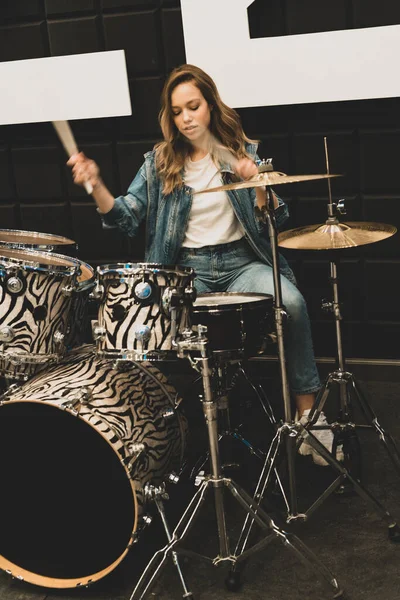 Creativity and music. Young beautiful girl plays the drums. Recording Studio. Musical equipment.
