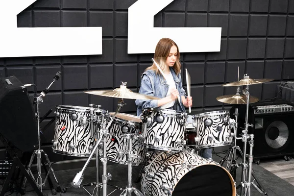 Creativity and music. Young beautiful girl plays the drums. Recording Studio. Musical equipment.