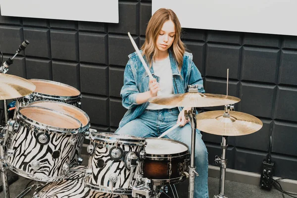 Creativity and music. Young beautiful girl plays the drums. Recording Studio. Musical equipment.