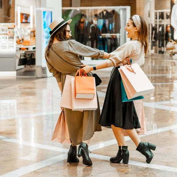 Shopping and entertainment, mall inside. Two beautiful girls with paper bags at the mall. The joy of consumption, Gift shopping, holiday.