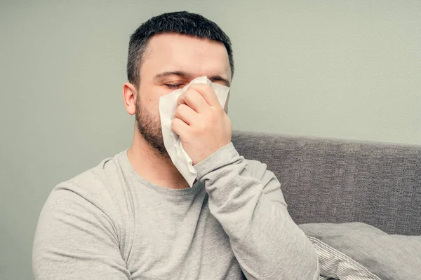 Disease. Cheer at home. A young man is sick, is treated at home. Blows her nose into a napkin, runny nose. Infection, epidemic, bacillus carrier.