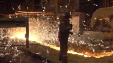Erimiş metal dökümhanesindeki adam, yüksek fırından dökülen erimiş sıvı metal.