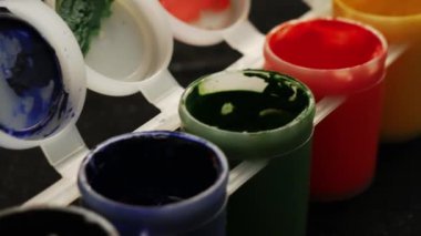 Plastik kavanoz üzerinde çok renk guaj seti. Çok renkli arka planı döndürün. Siyah arka plan üzerinde çeşitli boya guaj kavanoz bir sürü.