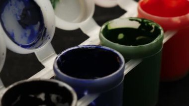 Plastik kavanoz üzerinde çok renk guaj seti. Çok renkli arka planı döndürün. Siyah arka plan üzerinde çeşitli boya guaj kavanoz bir sürü.