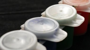 Plastik kavanoz üzerinde çok renk guaj seti. Çok renkli arka planı döndürün. Siyah arka plan üzerinde çeşitli boya guaj kavanoz bir sürü.