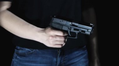 Siyah arka plandaki kız silahı yeniden yükler ve hedefi hedefletir. Close.