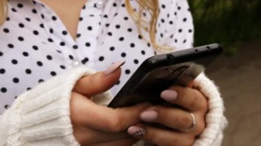 Yeşil park arka planında cep telefonu kullanan bir kadın. Eller akıllı telefondan mesaj yazıyormuş. Yaşam tarzı, internet, sosyal, çevrimiçi konsept.