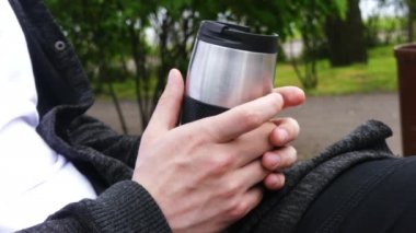 Çay ya da kahve molası. Genç adam parkta termosu, fincanı, kavanozu ya da çayı ya da kahveyi tutuyor. Tema seyahati veya eğlence. 
