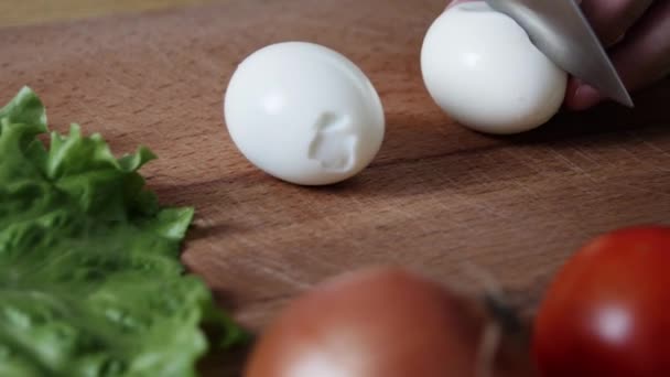 把煮熟的鸡蛋切两半 男子在厨房里用刀在菜板上切鸡蛋 切沙拉的配料 — 图库视频影像