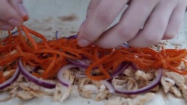 Döner kebap pişirme. Kadınların elleri kırmızı soğan ve haşlanmış tavuk eti üzerine marine havuç yayıldı.