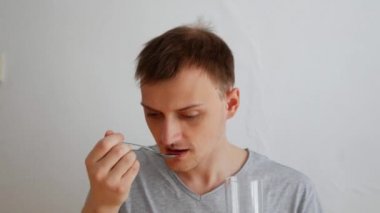 Genç bir adam bir bardak su ile ilaç içiyor