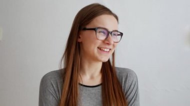 Genç kız gülüyor, beyaz arka planda yalnız duruyor.