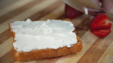 Taze kırmızı çilek ve ahşap bir tahta üzerinde beyaz süzme peynir Sandviç, yakın. Çilekli sandviç pişirme işlemi. Helthy gıda. 