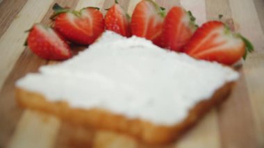 Taze kırmızı çilek ve beyaz süzme peynir sandviç ahşap bir tahta üzerinde, yakın, Yavaş yavaş odaklanarak. Çilekli sandviç pişirme işlemi. Helthy gıda. 