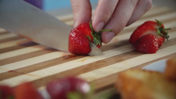 木製の板に新鮮なイチゴを切る男性の手 イチゴスライス イチゴサンドイッチ調理プロセス ヘルシーな食べ物 クローズアップ — ストック動画